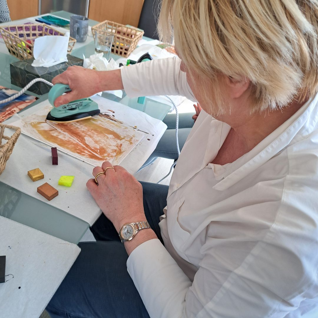 Creatieve werkvormen om te coachen - klant is aan de slag om een tekening met gekleurde bijenwas en strijkijzer te maken.